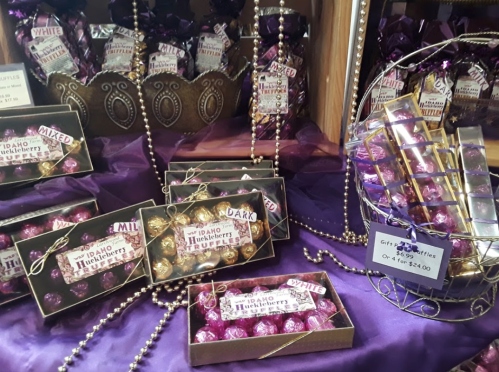 A display of assorted chocolate truffles in decorative boxes, with purple accents and a sign for gift truffles.