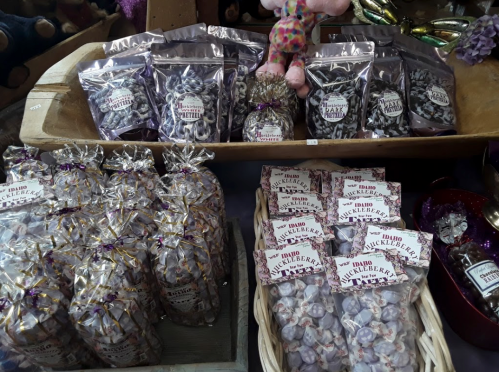 A display of various packaged candies, including huckleberry treats, in decorative bags and boxes.