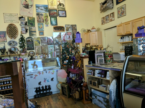 A cozy shop interior filled with various signs, decorations, and a display case, creating a warm, inviting atmosphere.