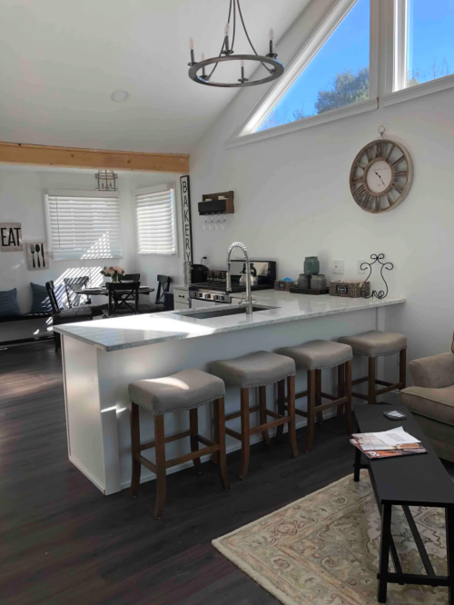 Bright kitchen with a large island, four stools, modern decor, and a cozy seating area with natural light.