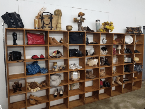 A wooden display shelf filled with various bags, shoes, and decorative items.