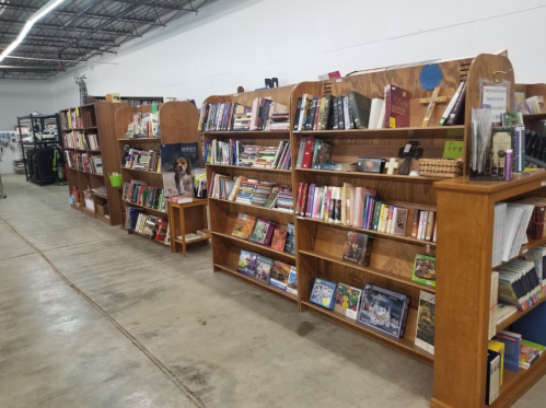 A row of wooden bookshelves filled with various books in a spacious, well-lit area.