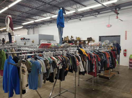 A spacious thrift store interior with clothing racks filled with various shirts and jackets.