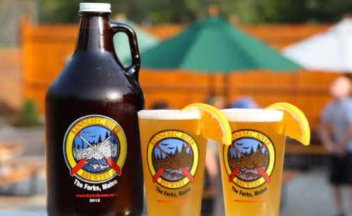 A growler and two glasses of beer with lemon slices, featuring the Kennebec River Brewery logo.