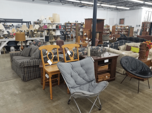 A spacious thrift store interior filled with various furniture items, including sofas, chairs, and tables.
