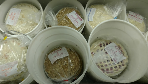 Buckets filled with various types of frozen pie crusts, each labeled with different flavors and ingredients.