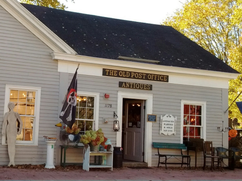 A quaint antique shop named "The Old Post Office" with a pirate flag and autumn decorations outside.