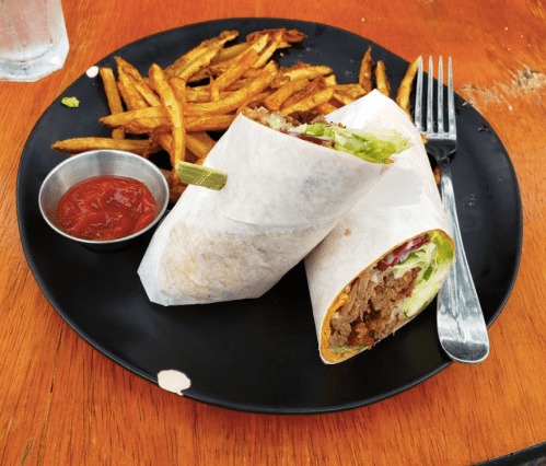 A plate with two wrapped burritos and a side of crispy fries, accompanied by a small bowl of ketchup.