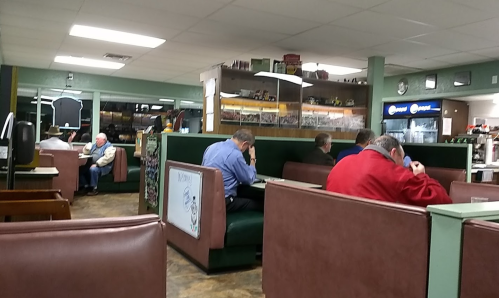A cozy diner interior with patrons seated in booths, enjoying meals and engaged in conversation.