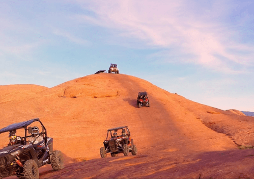 Off-road vehicles navigate a rocky landscape under a clear sky, showcasing adventure and rugged terrain.
