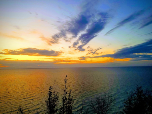 A serene sunset over the ocean, with vibrant colors reflecting on the water and clouds scattered in the sky.