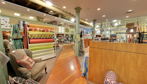 A spacious fabric store interior with colorful rolls of fabric, display furniture, and decorative items.