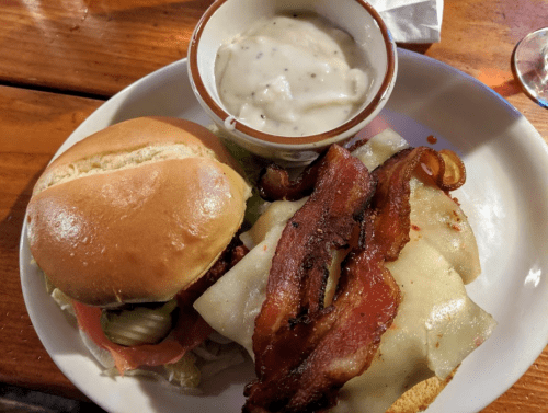 A plate with a sandwich featuring lettuce, tomato, and bacon, alongside a bowl of creamy soup.