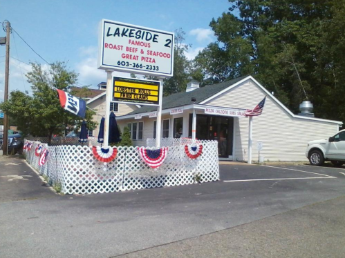 A restaurant named "Lakeside 2" with a sign advertising seafood and pizza, featuring patriotic decorations outside.