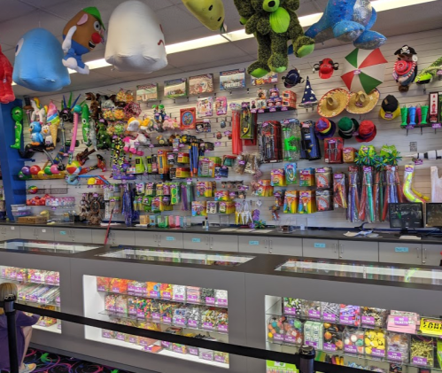 A colorful display of toys and novelty items on shelves, with a glass counter showcasing various candies and prizes.