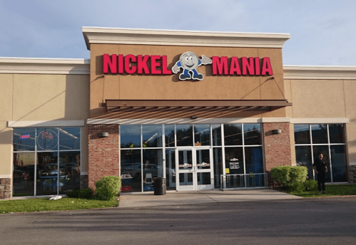 Exterior of Nickel Mania arcade, featuring a colorful sign and large windows, with a clear sky in the background.