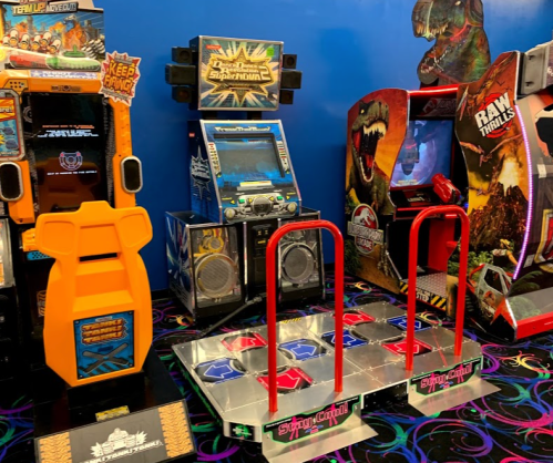 A colorful arcade featuring various games, including dance pads and themed machines against a blue wall.