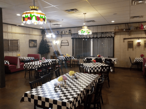 Cozy restaurant interior with checkered tables, colorful lamps, and floral centerpieces, featuring a warm, inviting atmosphere.