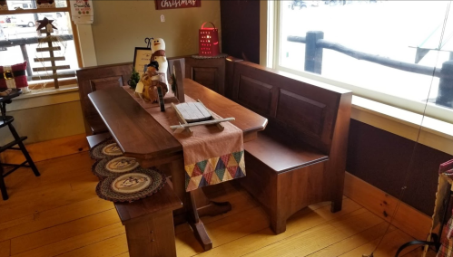 A cozy wooden dining nook with a table, benches, and decorative items, set in a warm, rustic interior.