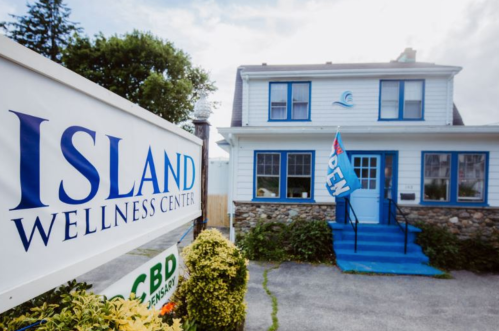 A wellness center with a blue and white exterior, featuring an "OPEN" flag and a sign that reads "Island Wellness Center."