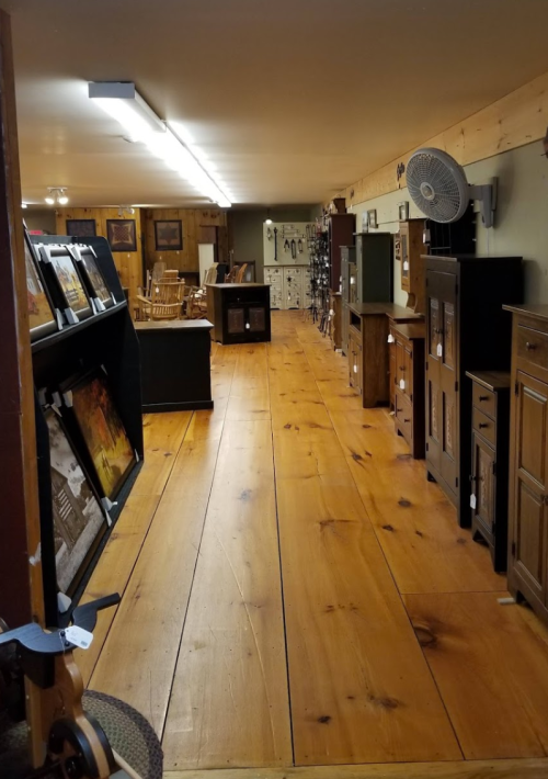 A spacious interior of a furniture store with wooden floors, displaying various furniture pieces and artwork.