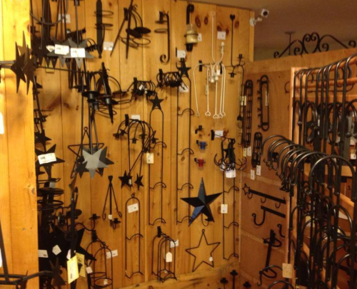 A display of various black metal hooks and decorative items hanging on a wooden wall.