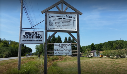 Sign for Community Market featuring metal roofing, fresh homemade donuts, and store hours.