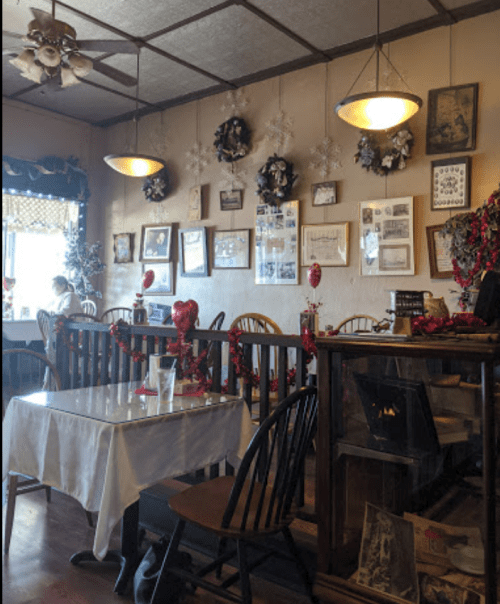 Cozy café interior decorated with wreaths and holiday decor, featuring wooden tables and a vintage display case.