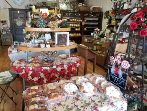 A cozy bakery display with festive decorations, featuring various baked goods and holiday-themed decor.