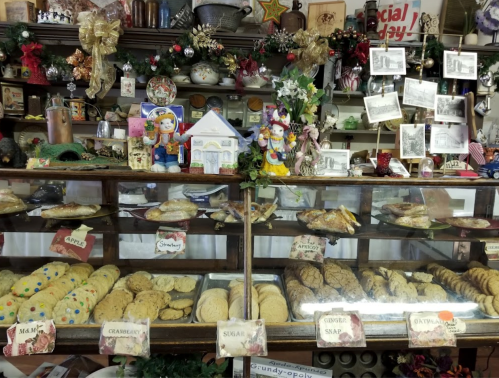 A display case filled with various cookies and baked goods, decorated with festive ornaments and holiday decor.