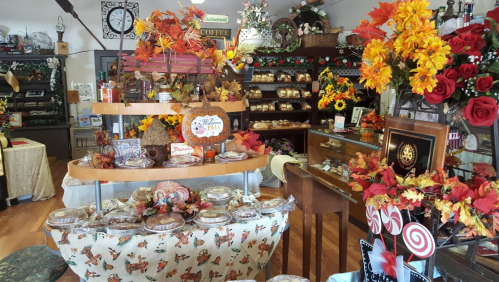 A cozy shop decorated with autumn leaves, baked goods, and seasonal decor, creating a warm, inviting atmosphere.