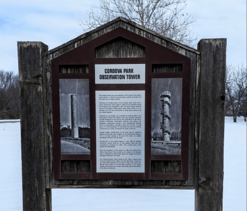 Sign for Cordova Park Observation Tower featuring historical photos and information, set against a snowy landscape.