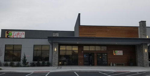 Exterior of Lefty's restaurant, featuring a modern design with stone accents and a colorful sign. Cloudy sky above.