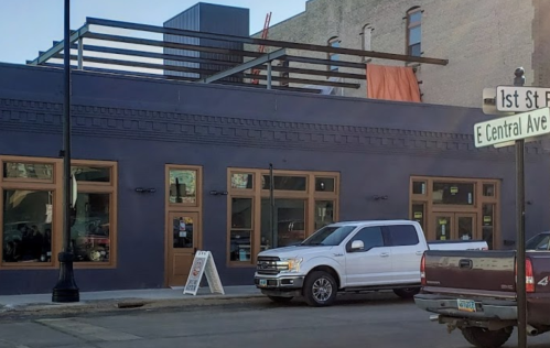 A modern building with large windows and a rooftop, located at the corner of 1st St and E Central Ave.