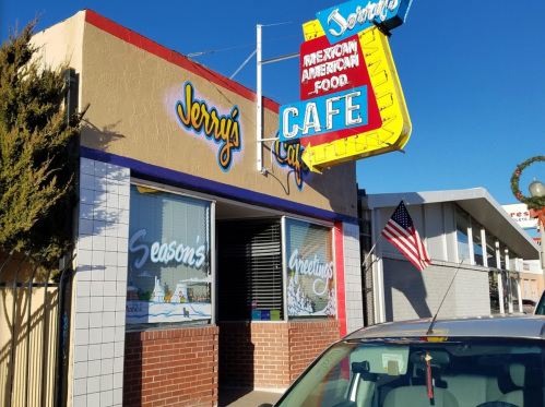 Exterior of Jerry's Cafe, featuring a colorful sign and festive window decorations, with an American flag nearby.