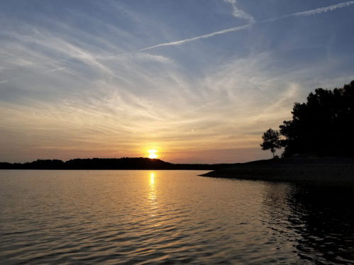 A serene sunset over a calm lake, with colorful clouds reflecting on the water's surface.