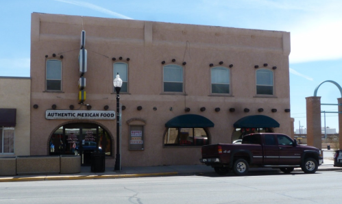 A pink building with green awnings and a sign reading "Authentic Mexican Food," parked truck in front.