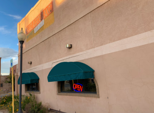 A building exterior with green awnings and an illuminated "OPEN" sign in the window.