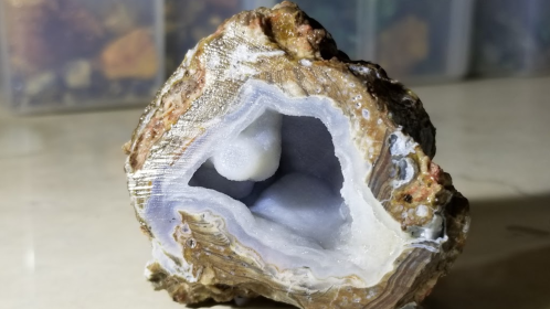 A geode with a rough exterior, revealing a smooth, crystalline interior with light blue and white formations.