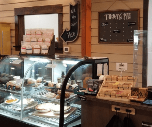 Display case filled with pies and baked goods, with a chalkboard sign reading "Today's Pie" in a cozy bakery setting.