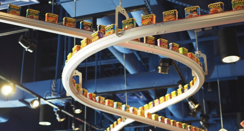 A spiral display of colorful Spam cans hanging from a ceiling in a modern setting.