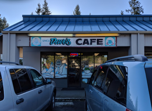 Exterior of Uncle Dave's Cafe with an "OPEN" sign, surrounded by parked cars and trees in the background.
