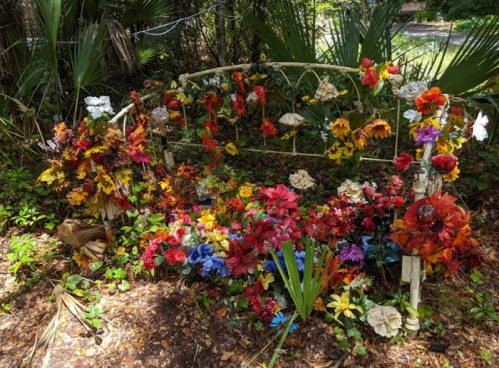 A decorative bed frame adorned with a vibrant array of artificial flowers in various colors, set in a lush garden.