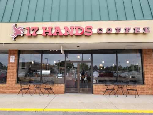 Exterior of 17 Hands Coffee shop with a green roof, brick facade, and outdoor seating.