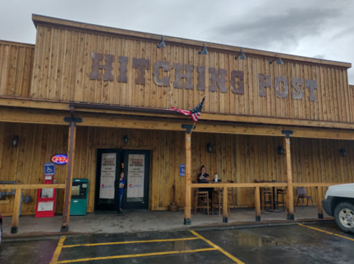 Exterior of the Hitching Post restaurant, featuring wooden walls, an open sign, and an American flag.