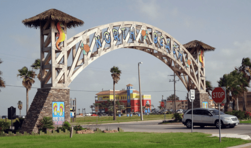 Colorful archway sign for North Beach, with palm trees and a stop sign in the foreground.