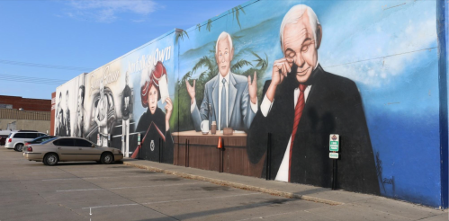 A colorful mural featuring three figures, including a man in a suit and a woman, set against a blue background.