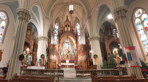Interior of a grand church featuring ornate architecture, stained glass windows, and a decorated altar.