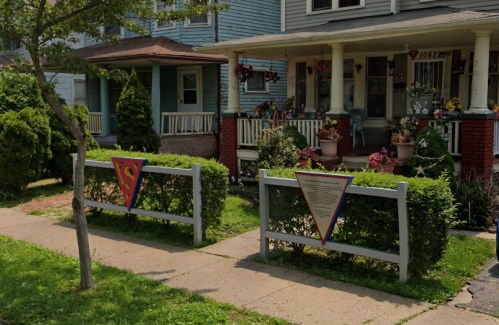 A residential street with two decorative fences and vibrant flower arrangements in front of two houses.
