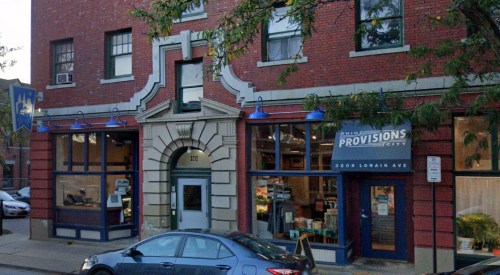 Exterior of a brick building featuring a storefront with large windows and a sign for "Ohio Provisions City."
